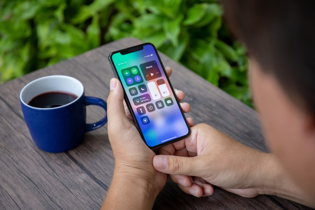 Koh Samui, Thailand - March 26, 2018: Hand Handing iPhone X with Domestic Screen Control Center. The iPhone 10 was created and developed by the Apple Inc.